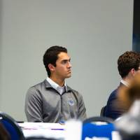 room full of people listening, a student in a gray athletic shirt is in focus